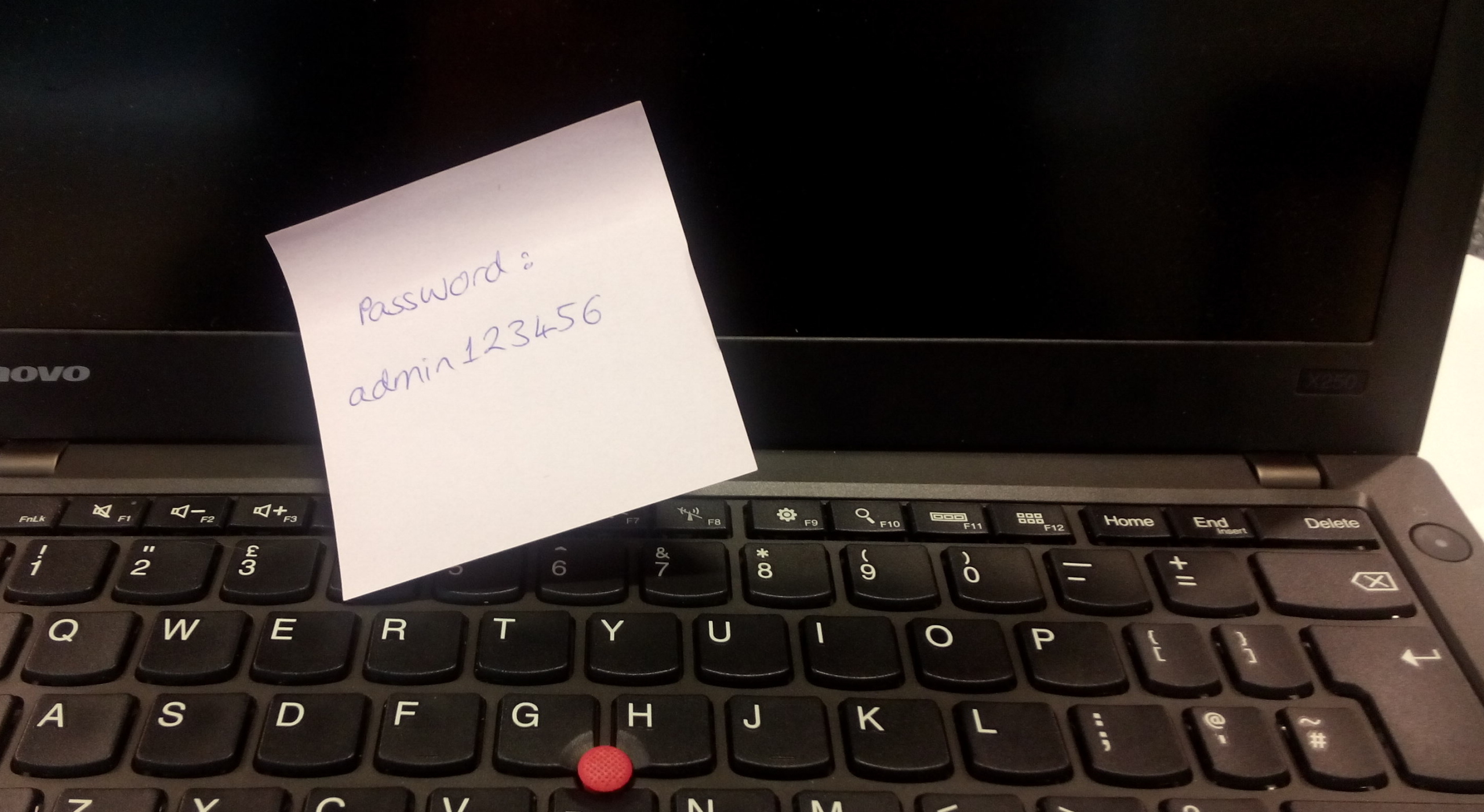 Photo of laptop with a post-it on providing the password