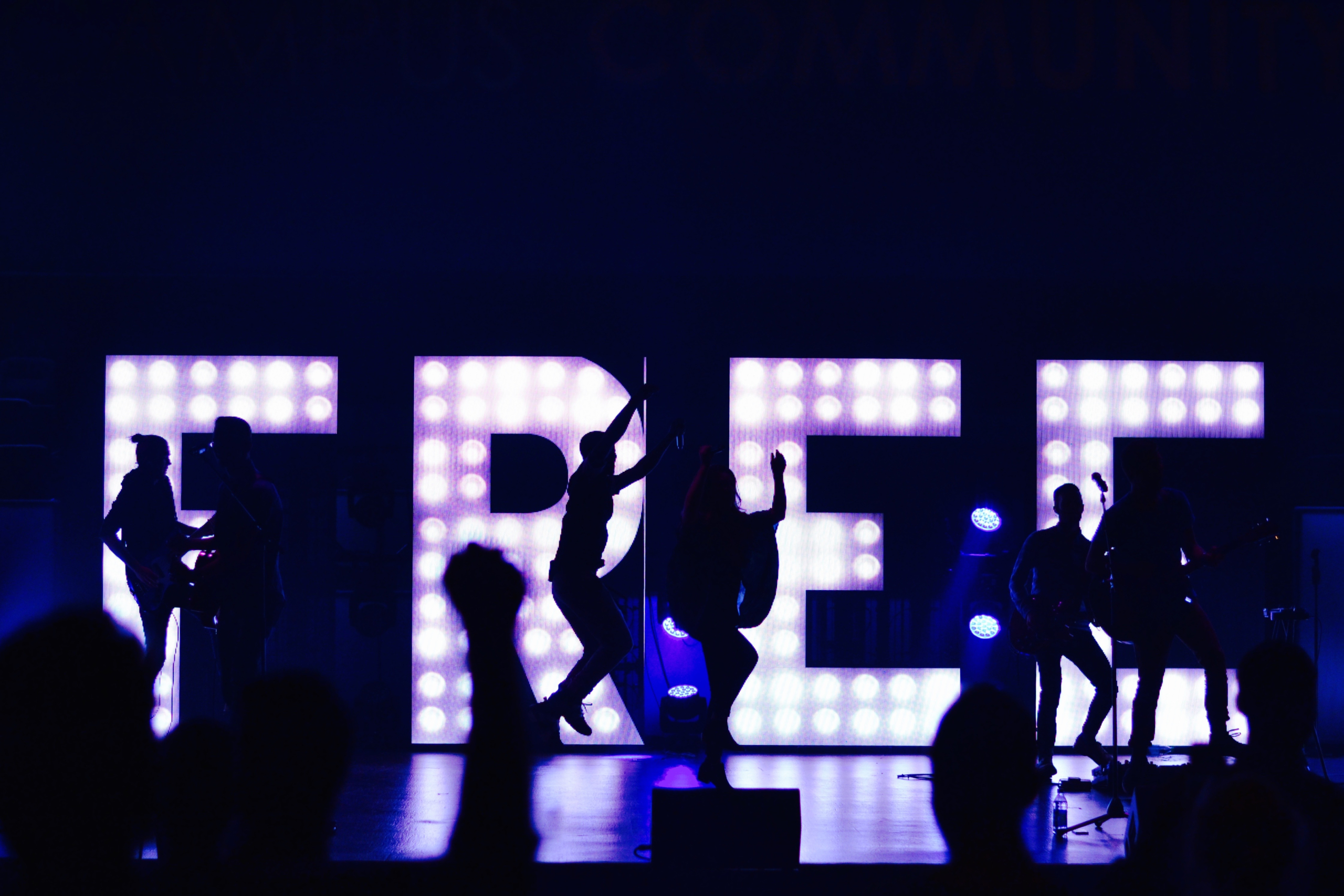 People dancing in front of a lit up sign reading Free