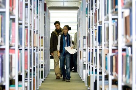 Students walking in the library shelving