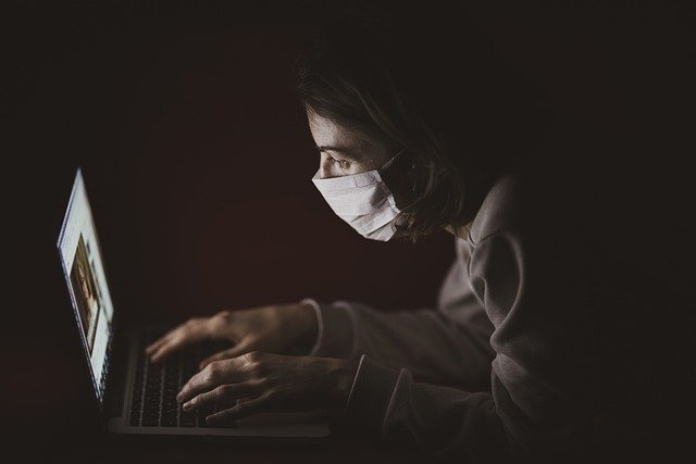 Woman in mask using laptop