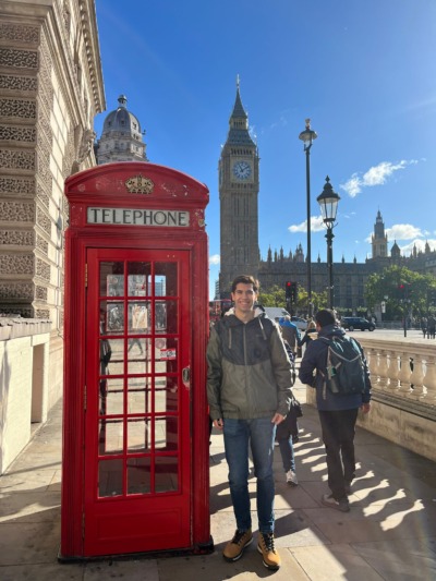 David leaning against a red post box in front of Big Ben in London.
